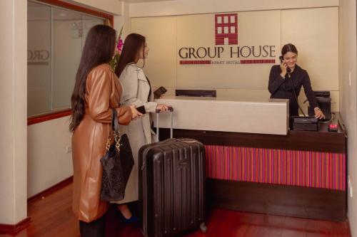 库斯科Group House Apart Hotel的两个女人站在柜台上,一个女人在说手机