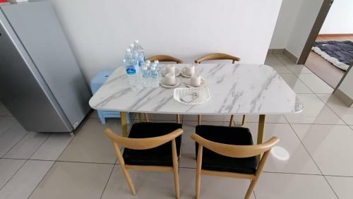 普崇16 Sierra Puchong Zentro 5 人 Supreme二房公寓的一张带四把椅子的白色桌子和一张白色大理石桌子