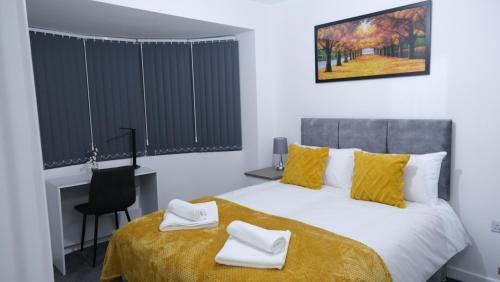 曼彻斯特EtihCity - 3 Bedroom Semi with Sky n Netflix near Etihad Football Stadium, Tourist attractions, Manchester City Centre Transport Links and Opposite to McDonald's的一间卧室配有一张带黄床单的床和一张书桌。