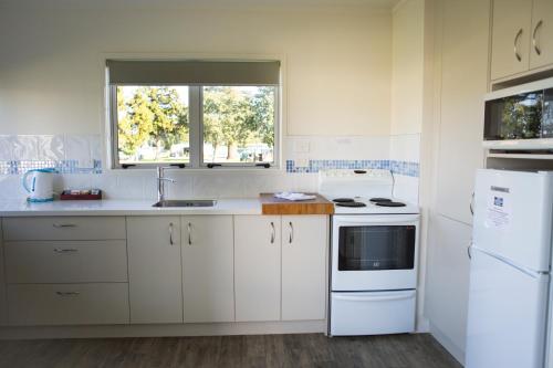 怀蒂昂格水星湾假日公园酒店的厨房配有白色橱柜、水槽和窗户。