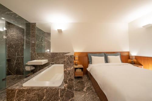 首尔首尔江南精品酒店的一间卧室配有一张床、一个浴缸和一个水槽