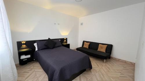 LíbanoAcogedor apartamento esquinero, a una cuadra del parque principal的一间卧室配有一张黑色的床和一张沙发