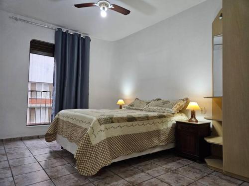 圣维森特岛Apê Itararé em São Vicente/SP的一间卧室配有一张床和吊扇