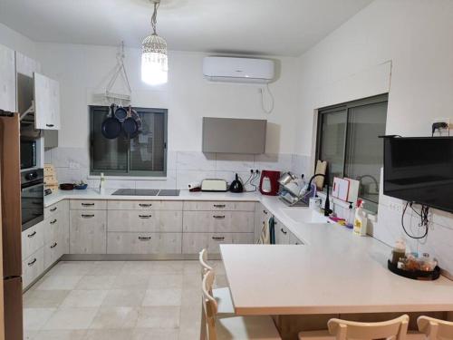 Kfar Yehezkelוילה בגלבוע的厨房配有白色橱柜和桌椅
