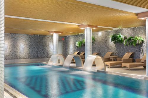 南泰利耶Best Western Plus Skogshöjd的酒店大堂的游泳池,配有椅子