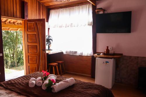 阿尤鲁奥卡Pousada Estalagem Mirante的一间卧室配有带毛巾的床和电视。