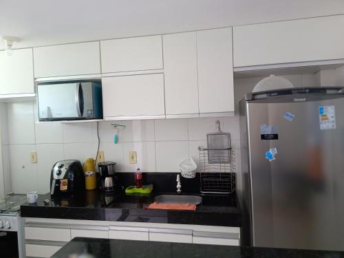 雅克南apartamento em Jacumã的厨房配有白色橱柜和黑色台面