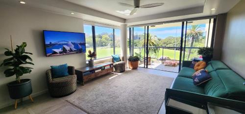 悉尼Contemporary Harbourside Apartment的客厅配有绿色沙发和平面电视