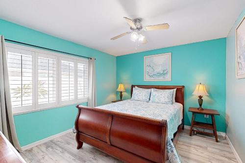 威尼斯Coastal Hideaway的一间卧室设有蓝色的墙壁、一张床和吊扇。