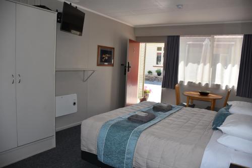 Roxburgh罗克斯堡汽车旅馆的一间卧室配有一张床、一台电视和一张桌子