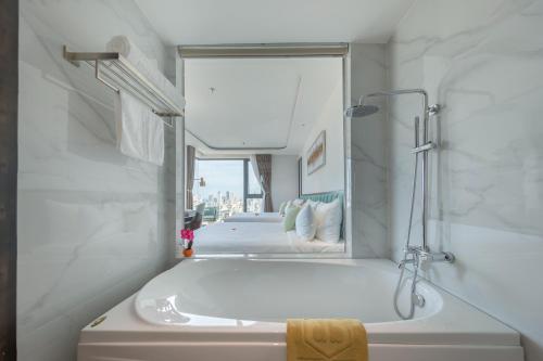 岘港Cordial Hotel and Spa的白色的浴室设有浴缸和镜子