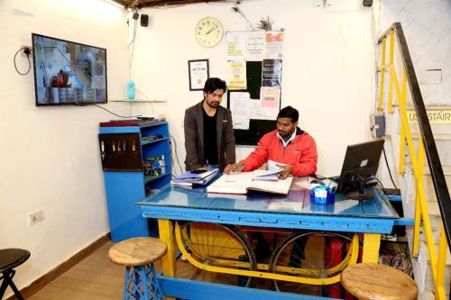 新德里Bunk Hostel Delhi Best Backpacking Accommodation的两个人坐在一张桌子上,手提电脑