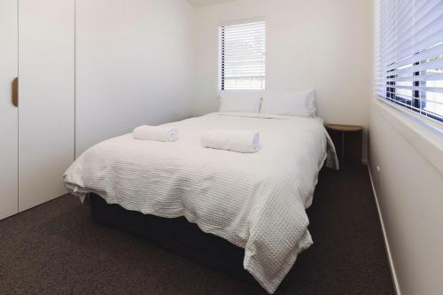 新普利茅斯Lovely on Lismore的一间卧室配有一张带白色床单的床和一扇窗户。
