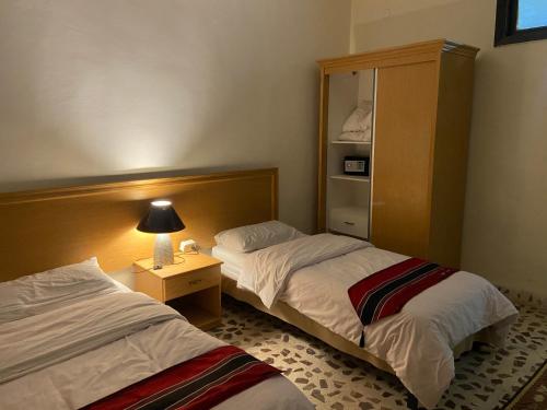 马达巴Madaba Mesha Stele Bedoiun Apartments的酒店客房设有两张床和床头柜。