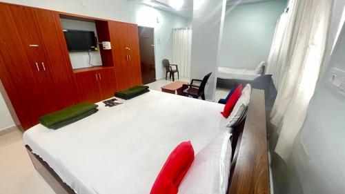 海得拉巴Brundavan的卧室配有带红色枕头的大型白色床