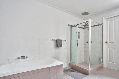 悉尼Family Friendly 3 Bedroom House Glebe 2 E-Bikes Included的带浴缸和玻璃淋浴间的浴室。