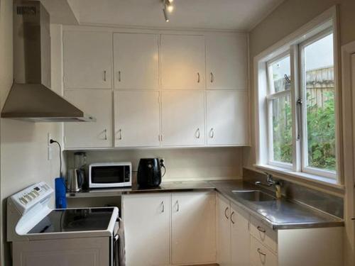 惠灵顿Wellington single bedroom的厨房配有白色橱柜、水槽和微波炉