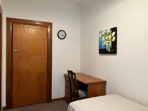 惠灵顿Wellington single bedroom的一间设有书桌的房间和一个带时钟的门