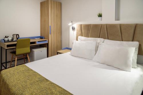 提比里亚Lago Hotel的一间卧室配有一张带白色枕头的床和一张书桌