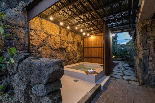 济州市Bijarim Healing Pension的一间石墙内带浴缸的浴室