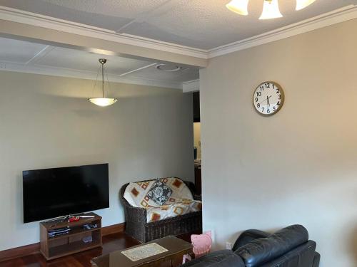 惠灵顿Wellington single bedroom的客厅配有沙发和墙上的时钟