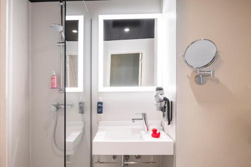 迭戈姆布鲁塞尔机场托恩酒店的浴室配有盥洗盆和带镜子的淋浴