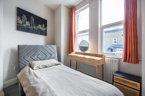 伦敦Cosy 1 Bed apartment with FREE PARKING close to Underground station zone 2 for quick access to Central London up to 5 guests的一间卧室配有一张床、一张书桌和一个窗户。