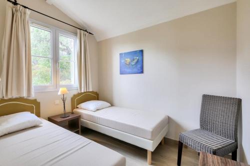 格里莫Les Bastides aux Restanques du Golfe de St Tropez - Maeva Home - Bastide spac 59的客房设有两张床、一把椅子和窗户。