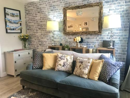 彭布罗克郡Charming Coastal Getaway - Pembroke的客厅配有蓝色的沙发和镜子