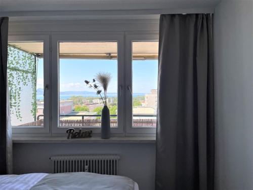 洛豪Apartment mit Terassee & Aussicht auf See und Berge的一间卧室,窗户上装有鲜花花瓶