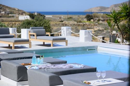 法蒂亚Mykonos Dream Villas的一个带躺椅和桌子及酒杯的游泳池