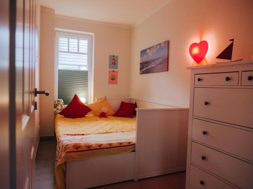 伯尔格伦德-雷特维施Ferienwohnungen Parkstraße的小卧室配有红色枕头的床