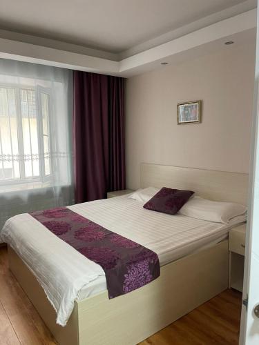 乌兰巴托Mandarin的一间卧室配有一张带紫色棉被的床