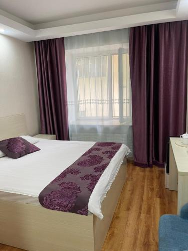 乌兰巴托Mandarin的一间卧室配有一张带紫色窗帘的床和窗户。