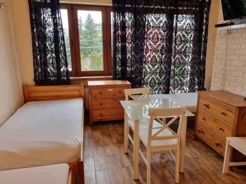 弗罗茨瓦夫Hostel Rumiankowy Airport Hostel的一间卧室设有两张床、一张桌子和一个窗口