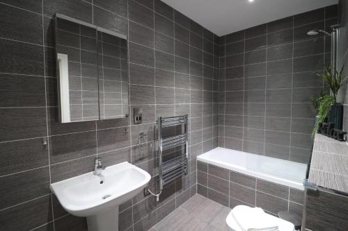 利明顿温泉The Windsor Club Apartment的浴室配有盥洗盆、卫生间和浴缸。