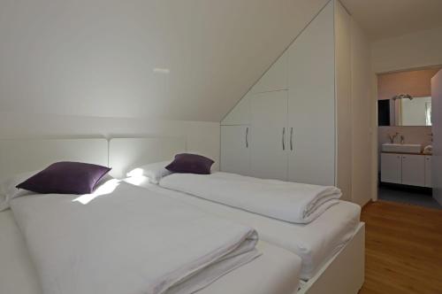 上拉德戈纳Hiša Štolc的卧室配有一张带紫色枕头的大型白色床。
