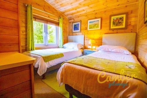 BrooklandRainbow Petty - Pine lodge - Kent countryside的小木屋内一间卧室,配有两张床