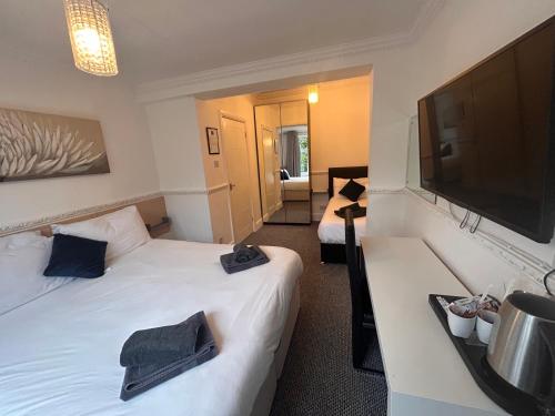 拉夫堡Charnwood Regency Guest House的酒店客房设有两张床和一台平面电视。