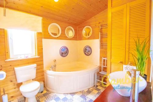 BrooklandTore Petty - Romantic lodge - spa bath and sauna的带浴缸、卫生间和盥洗盆的浴室