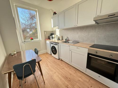 不来梅港Gemütliche Retro Wohnung的厨房配有白色橱柜、桌子和窗户。