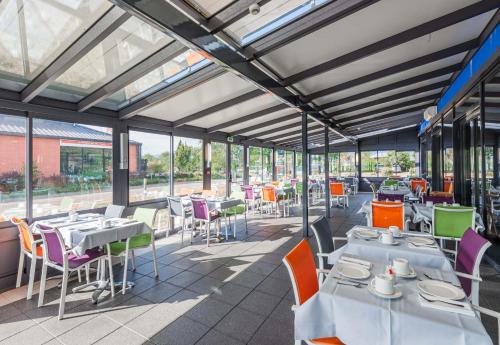 科尔马B&B HOTEL Colmar Liberté 4 étoiles的餐厅设有桌椅和窗户。
