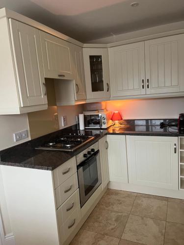 阿德莫尔Ardmore Village Family Home的厨房配有白色橱柜和炉灶烤箱。