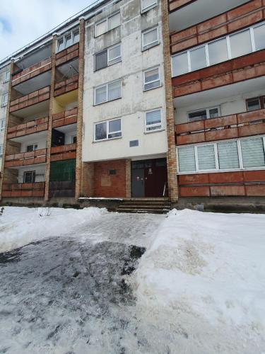 萨拉斯皮尔斯Salaspils Apartament 2023的公寓大楼前面有雪