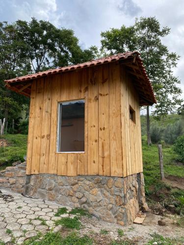 CristinaSítio paiol Velho的一座小木房子,在石头地基上设有窗户