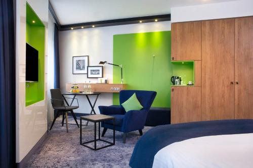 斯图加特斯图加特假日酒店的一间卧室配有一张床和一张书桌,并拥有绿色的墙壁