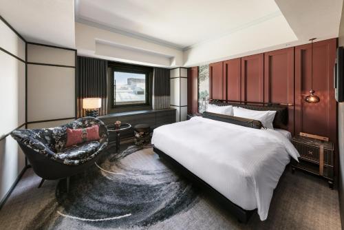 札幌Hotel Sosei Sapporo MGallery Collection的一间卧室配有一张大床和一把椅子