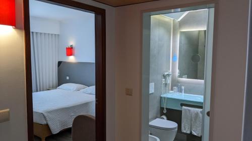 波瓦-迪瓦尔津瓦尔津酒店的一间带一张床的卧室和一间带镜子的浴室