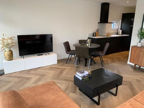 埃尔默洛Luxe boshuisje Arlo in Ermelo!的客厅配有平面电视和桌子。