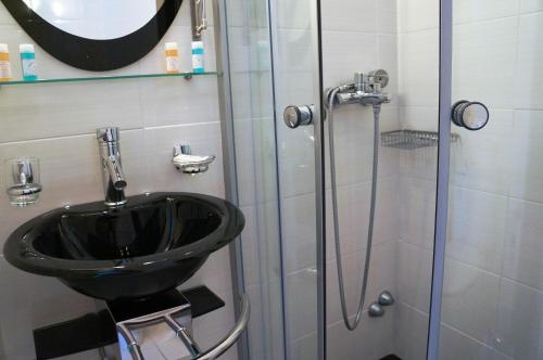 斯科拉Captain's House Hotel的一间带黑色水槽和淋浴的浴室